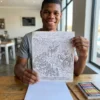 A person colouring a printed page from the The Holy Bible coloring book